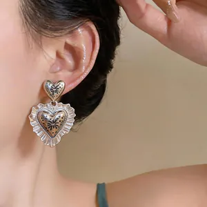 Close-up detail of vintage silver heart earrings with ruffled edges on a model's ear.