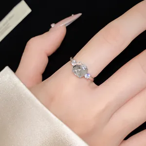 Detail view of a minimalist silver open ring featuring a cushion-cut zircon stone.