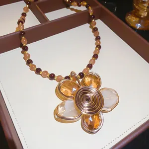 Dettaglio di una collana vintage di perle con ciondolo a fiore avvolto in filo metallico