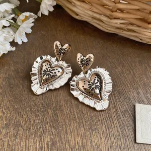 Detail view of vintage lace heart stud earrings in Maillard style gold tone