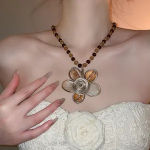 Vista dettagliata di una collana di perle vintage con grande ciondolo a fiore indossata da modella