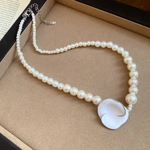 Dettaglio macro di una collana di perle in stile francese con ciondolo a fiore bianco