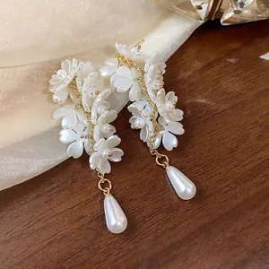 Close-up detail of French style white floral tassel earrings with elegant teardrop pearls
