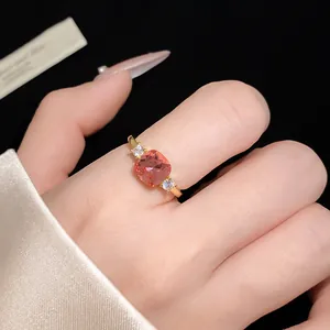Close-up detail of an elegant gold open ring featuring a square pink zircon and clear stones