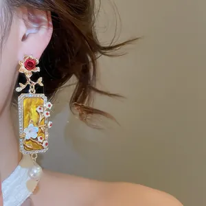 Dettaglio ravvicinato di orecchini pendenti vintage stile corte con fiori e perle