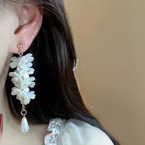 Detailed view of elegant French-style white floral tassel earrings with pearl drop on ear