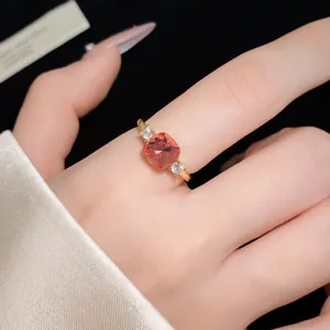 Detail view of a square pink zircon open ring on a model's finger with gold finish
