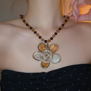 Collana vintage stile corte con catena di perline e grande ciondolo a fiore intrecciato.
