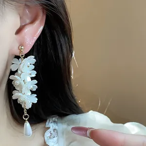 Macro detail view of elegant French style white flower tassel earrings with pearl drop