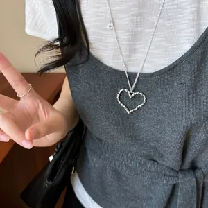 Close-up of model wearing a textured hollow heart pendant necklace in silver finish.