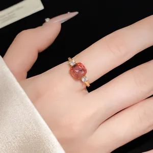Close-up detail of a gold open ring featuring a sparkling pink square zircon gemstone.