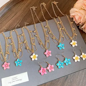 Detail showing vintage enamel flower necklace and earring set in pink, blue and yellow.