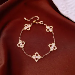 Detailaufnahme eines goldenen Kleeblatt-Armbands mit funkelnden Zirkonia-Steinen.