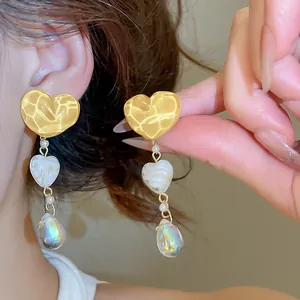 Close-up detail of vintage-style yellow heart tassel earrings with pearlescent drop beads