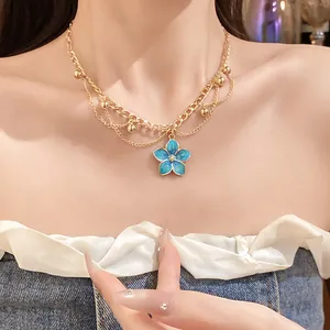 Detailed view of double-layered gold chain necklace featuring a blue enamel flower pendant