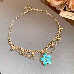 Detailed view of vintage gold-tone necklace with a blue floral pendant and bead accents