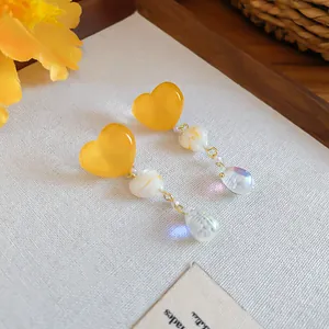 Detail of vintage irregular yellow heart tassel earrings with iridescent beads