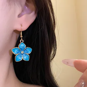 Detailed view of elegant blue enamel flower drop earring shown on model with long dark hair