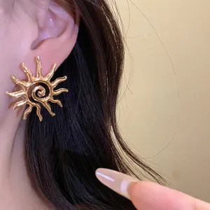 Elegant golden sun-shaped stud earring with hollow spiral design on model