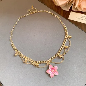 Detailed close-up of a vintage gold chain necklace featuring a pink enamel flower pendant