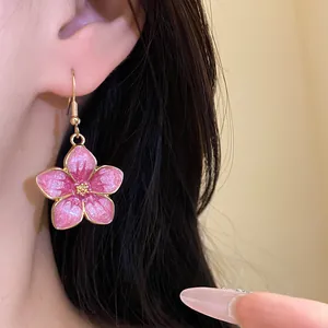 Close-up of a vintage pink cherry blossom earring with glitter finish worn on ear
