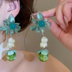 Detailed view of green floral dangle earrings with pearly accents and large round beads