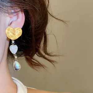 Close-up view of vintage irregular yellow heart dangling earrings worn on a model's ear