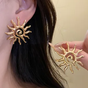 Close-up detail of golden sun-shaped hollow earrings with unique spiral center