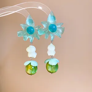 Close-up of sweet summer flower drop earrings with teal petals and green beads.