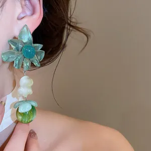 Close-up detail of sweet green flower pendant earrings for a summer beach vacation look