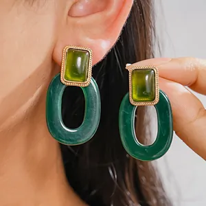 Detaillierte Nahaufnahme von grünen Vintage-Harzohrringen mit quadratischem Oval-Design.