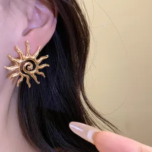 Detailed macro view of gold sun-shaped stud earring with spiral texture worn on ear