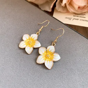 Macro detail showing the elegant yellow and white enamel flower drop earrings set