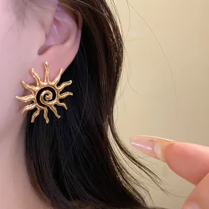 Close-up view of a stylish golden sun-shaped hollow stud earring worn on a female ear