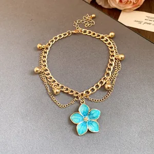 Close-up of a vintage gold-toned anklet featuring a detailed blue flower pendant.