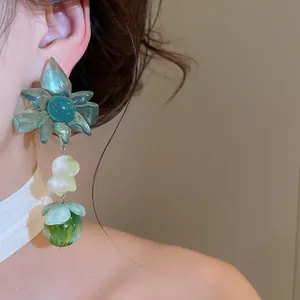 Close-up view of green resin floral drop earrings worn by a model for summer style.