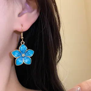 Close-up detail of a vintage blue oil-drip flower earring with gold trim worn by a model