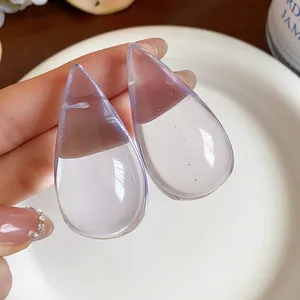 Detalle macro de elegantes pendientes de gota en resina púrpura clara con aguja de plata