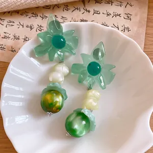 Detailed view of sweet green flower drop earrings with marble effect beads in a white shell
