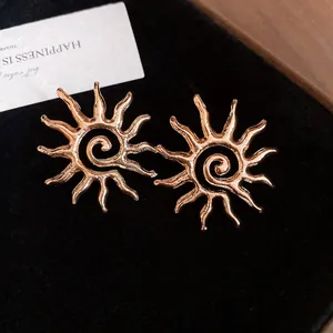 Detailed close-up of rose gold sun-shaped hollow metal stud earrings with spiral center