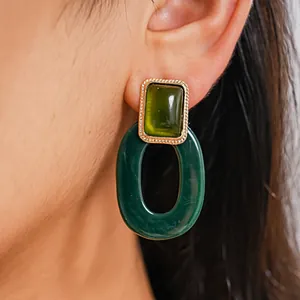 Detaillierte Nahaufnahme von grünen Retro-Harzohrringen mit ovalem Reifen am Ohr des Modells