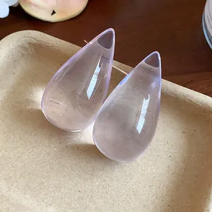 Vista detallada de pendientes de gota en resina púrpura sobre una bandeja