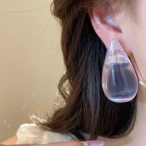 Primer plano de un pendiente de gota de resina púrpura que muestra su textura transparente.