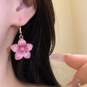 Detailed close-up showing the pink cherry blossom enamel dangle earring on an ear