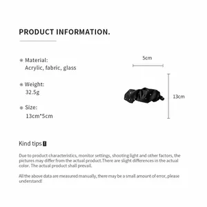 Dettaglio che mostra dimensioni e materiali del fermaglio a banana in tessuto nero.