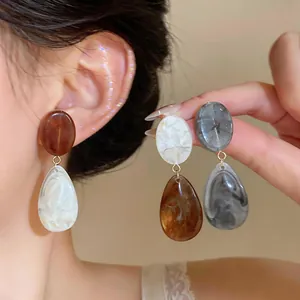 Detailed macro view of retro resin water-drop earrings in Maillard brown and marble white