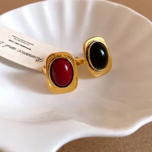 Detailed view of two vintage-style square open rings with red and black oval stones
