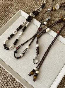 Detailansicht von braunen Taillenketten im Boho-Stil mit Muschel- und Holzperlen