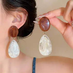Close-up of resin teardrop earrings with Maillard style marble texture