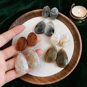 Detail of vintage resin waterdrop earrings in various marbled colors on wooden tray